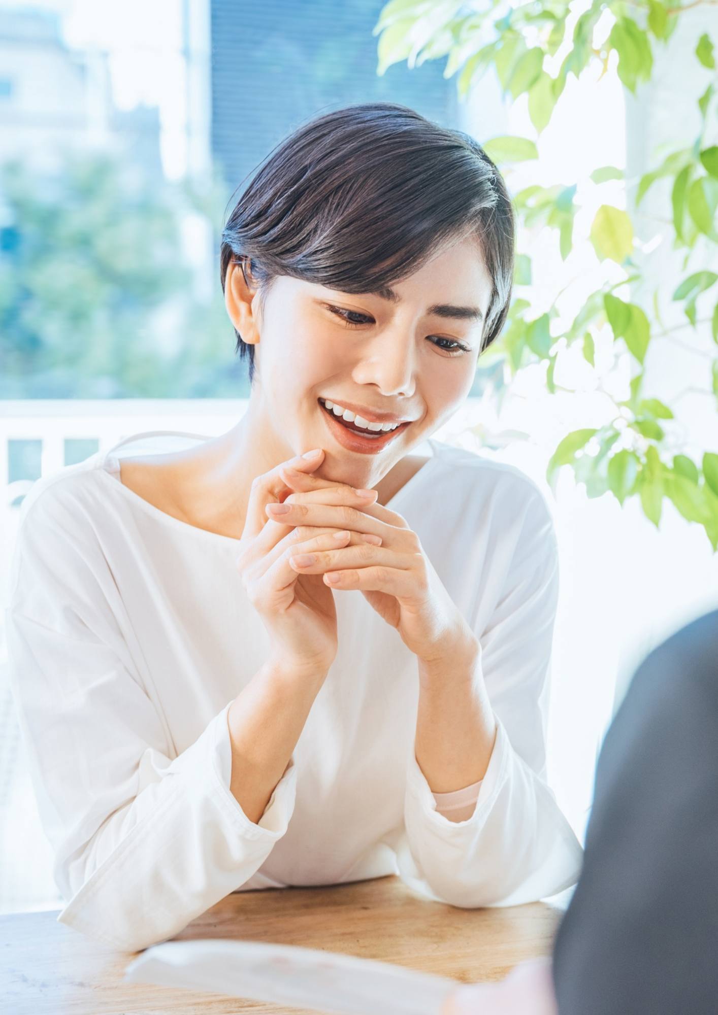 Smiling woman talking with a psychologist in a bright, plant-filled room